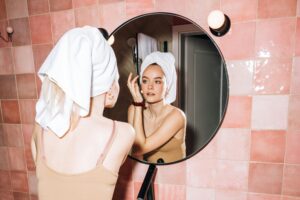 Female checking her complexion in a mirror, illustrating skincare and aesthetic wellness.